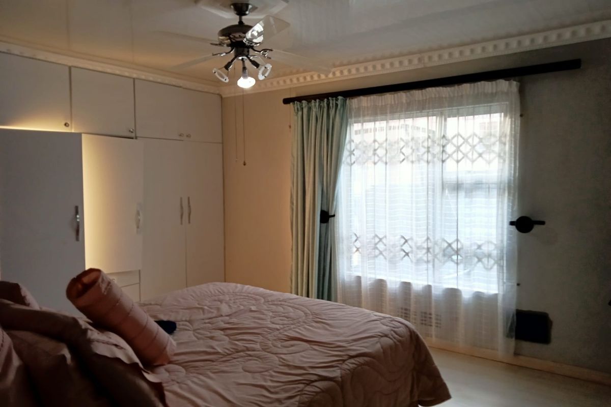A bedroom featuring built-in cupboards, a ceiling fan, and decorative ceiling cornices, providing functional storage and classic architectural detailing.