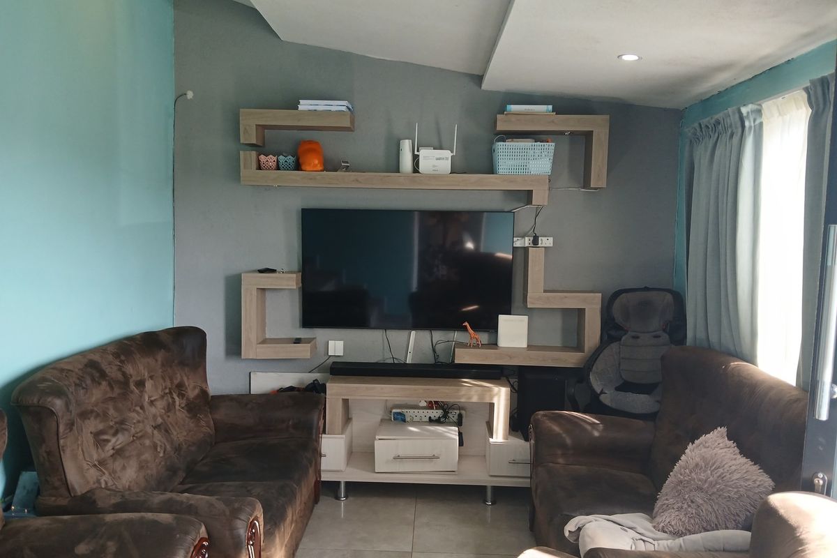 A living room featuring a modern built-in wall shelving unit, tiled flooring, and recessed ceiling lighting.
