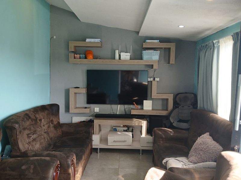 A living room featuring a modern built-in wall shelving unit, tiled flooring, and recessed ceiling lighting.