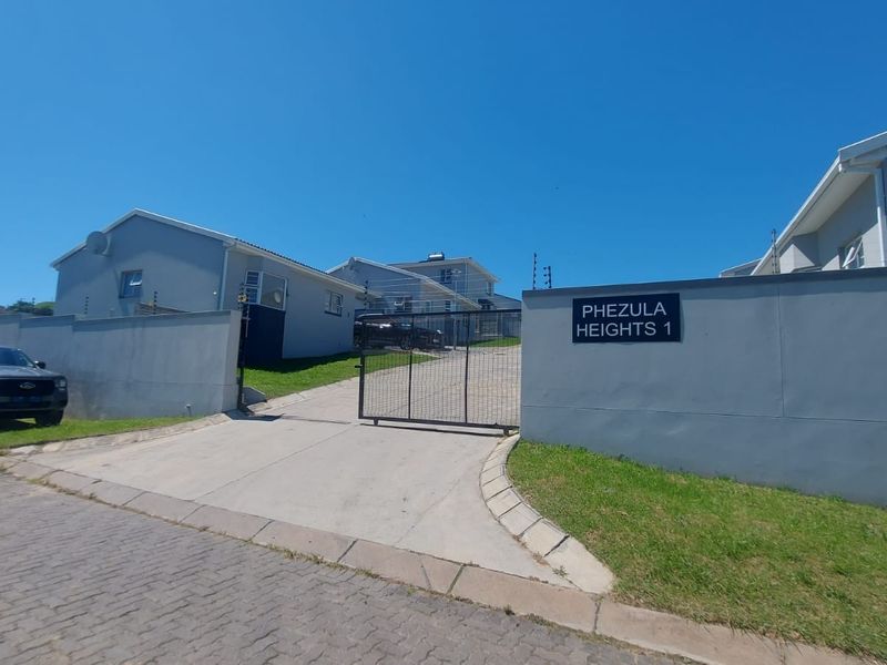 Front entrance view of Phezula Heights 1 townhouse complex featuring a secure gated driveway, perimeter walling, and electric fencing.