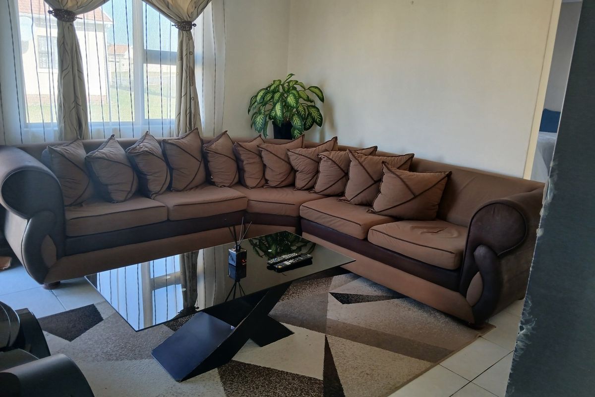 A comfortable living room featuring tiled flooring and a large window that allows for natural light.