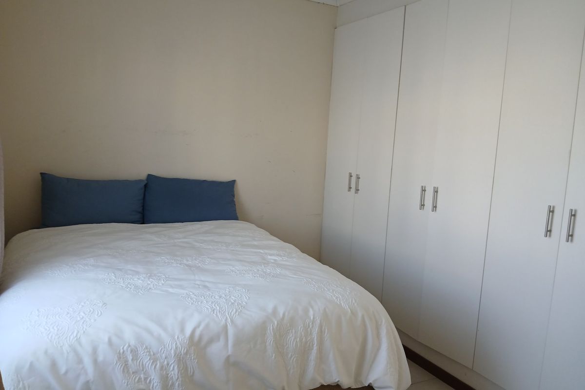 A bedroom featuring white built-in cupboards and neutral wall finishes.