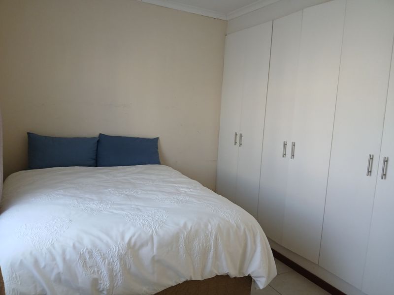 A bedroom featuring white built-in cupboards and neutral wall finishes.