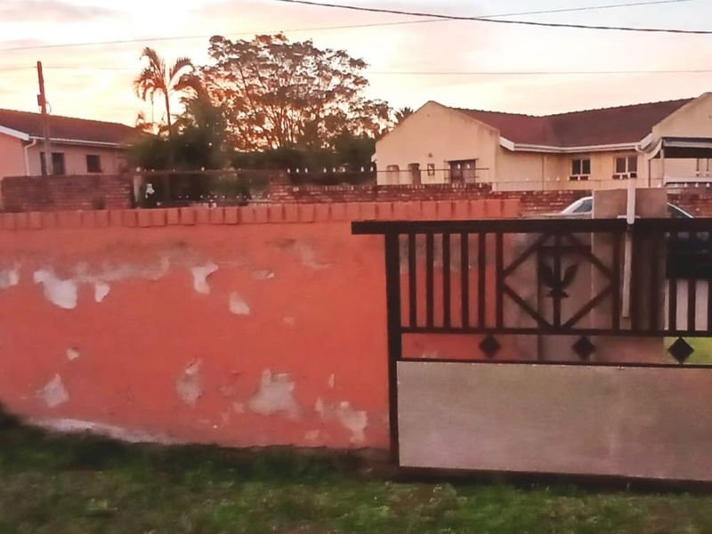 Front view of the property featuring a perimeter wall with a metal driveway gate and a view of the residential structure.