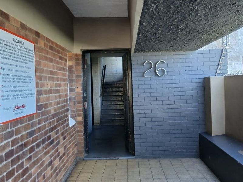 Front entrance area featuring brick facade, tiled flooring, and access to an internal staircase, marked with unit number 26.
