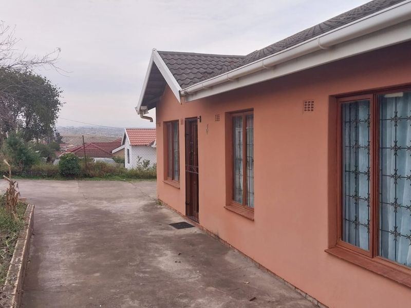 Exterior view of the office building featuring a tiled roof, security bars on windows, and a concrete driveway.