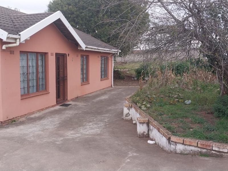 Exterior view of the office building featuring a concrete driveway, tiled roof, and a brick retaining wall in the front garden area.