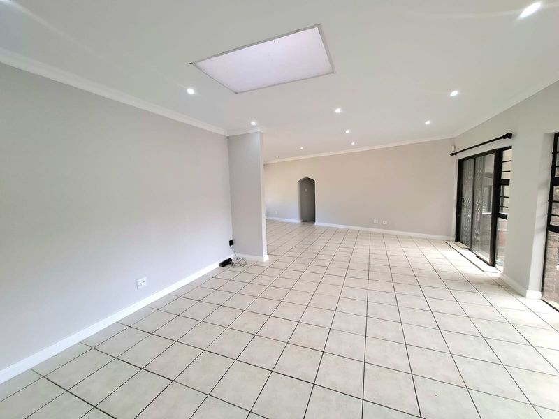 Spacious open-plan living area featuring neutral tiled flooring, recessed downlighting, and a large skylight, providing a bright and versatile blank canvas.