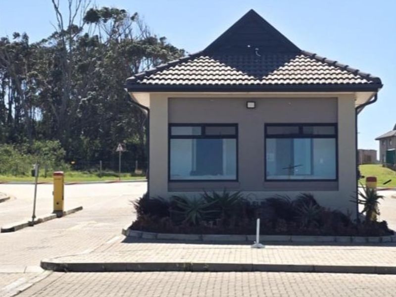 A well-maintained security gatehouse at the entrance of the apartment complex, featuring a tiled roof and automated boom gate access control.