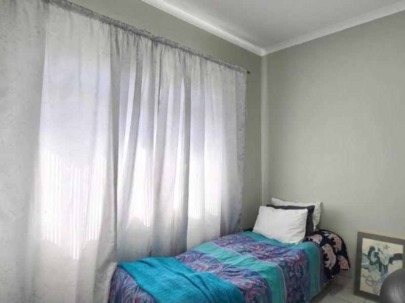 A compact bedroom featuring neutral wall paint, cove cornicing, and a built-in cupboard with a modern handle.