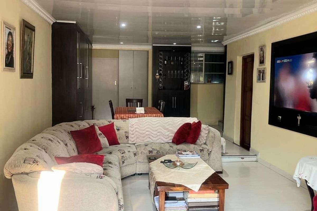A living room featuring glossy ceiling panels, tiled flooring, and built-in cabinetry, offering a functional space with integrated storage solutions.