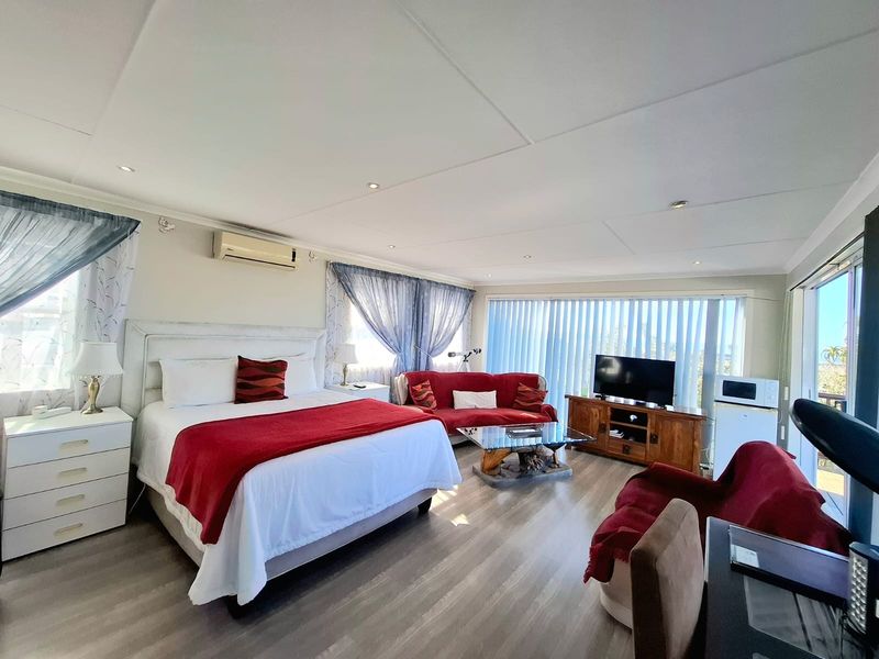 Spacious bedroom featuring laminate flooring, recessed lighting, a split-system air conditioner, and large windows with vertical blinds providing natural light.