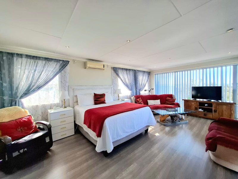 Spacious bedroom featuring laminate flooring, recessed downlighting, and a wall-mounted split-system air conditioner, offering a comfortable and functional living space.