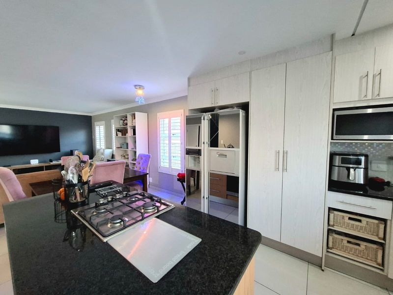 Open-plan living area featuring a modern kitchen with a granite island, gas hob, and ample built-in cabinetry, seamlessly flowing into the lounge space.