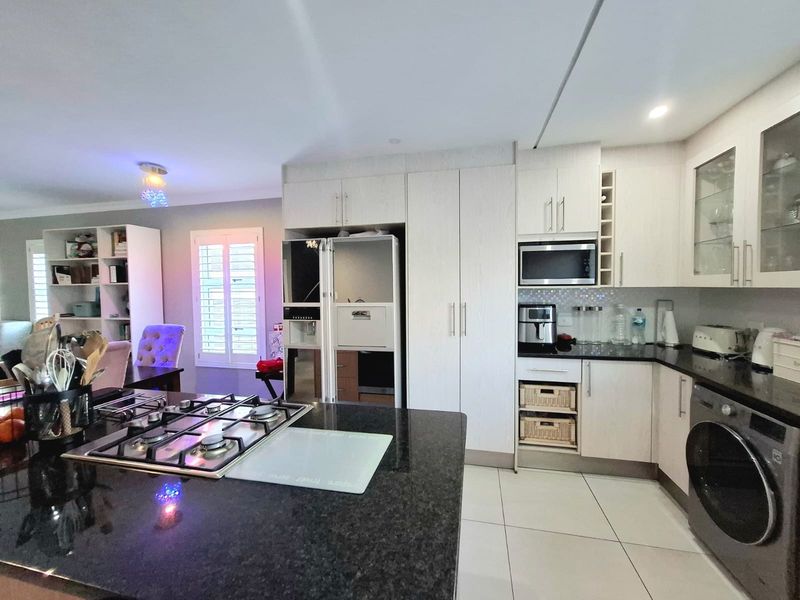 Modern open-plan kitchen featuring granite countertops, gas cooktop, built-in microwave, and ample cabinetry, seamlessly flowing into the adjacent living and dining area.