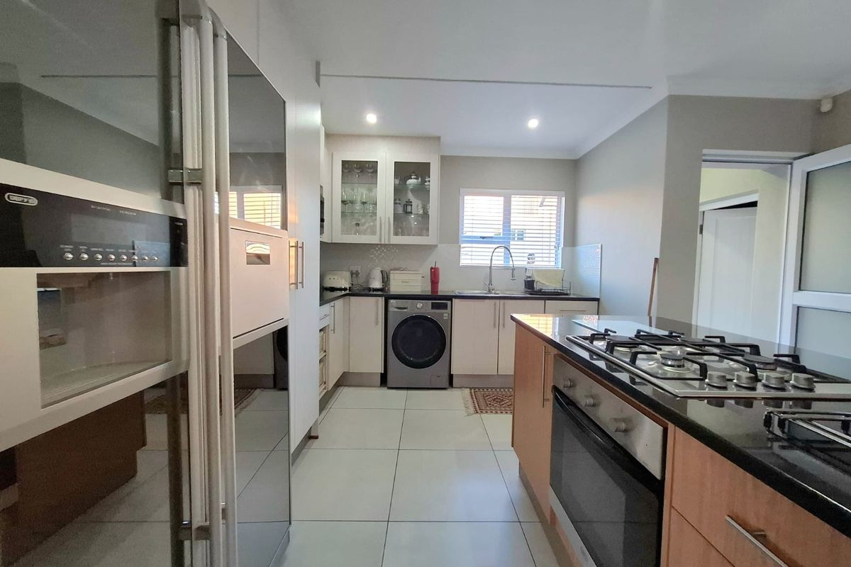 Modern kitchen featuring granite countertops, built-in oven, gas hob, and ample cabinetry with tiled flooring and recessed lighting.