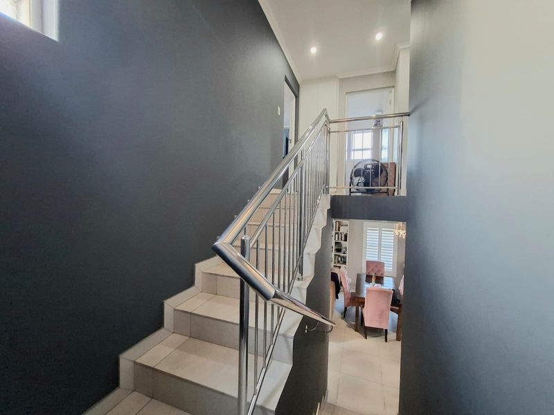 A modern staircase featuring tiled steps and a sleek stainless steel balustrade, connecting the levels of this contemporary townhouse.
