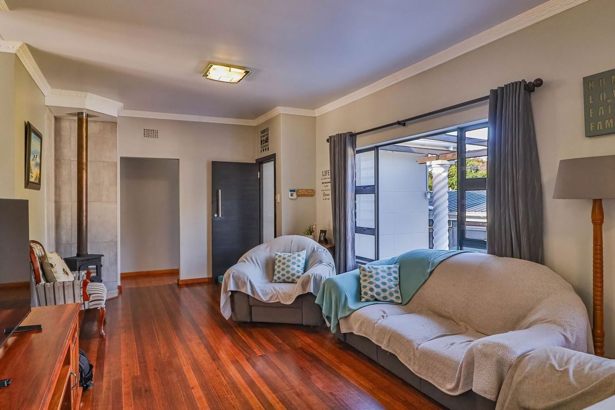A well-maintained living room featuring polished hardwood floors, a striking stone feature wall, and a cozy freestanding fireplace with direct access to the patio.