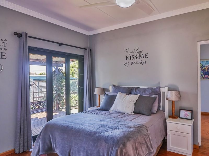 A well-maintained bedroom featuring hardwood flooring, crown molding, a ceiling fan, and sliding glass doors providing direct access to an outdoor patio area.