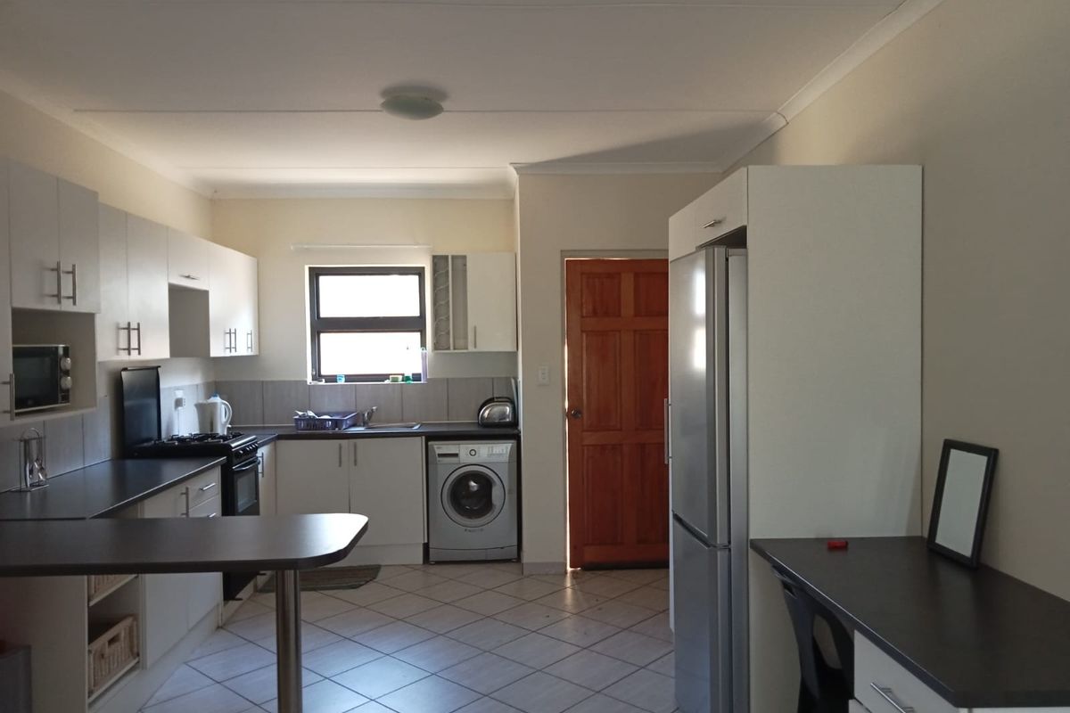 Functional kitchen featuring white cabinetry, dark laminate countertops, built-in oven and hob, tiled flooring, and a convenient breakfast nook area.