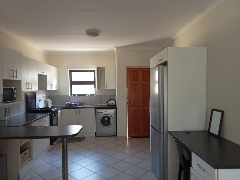 Functional kitchen featuring white cabinetry, dark laminate countertops, built-in oven and hob, tiled flooring, and a convenient breakfast nook area.