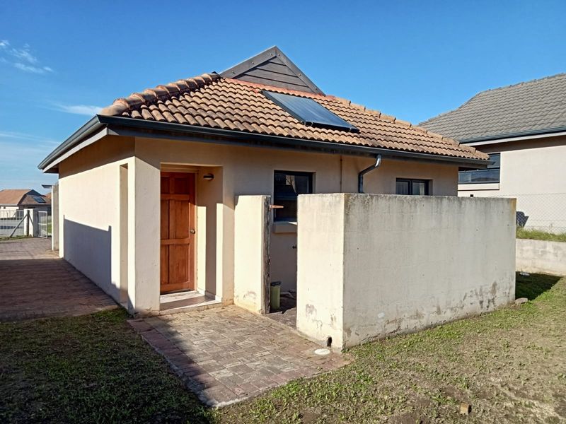 Rear view of the cluster property featuring a tiled roof with a solar water heater, a paved walkway, and a private boundary wall.