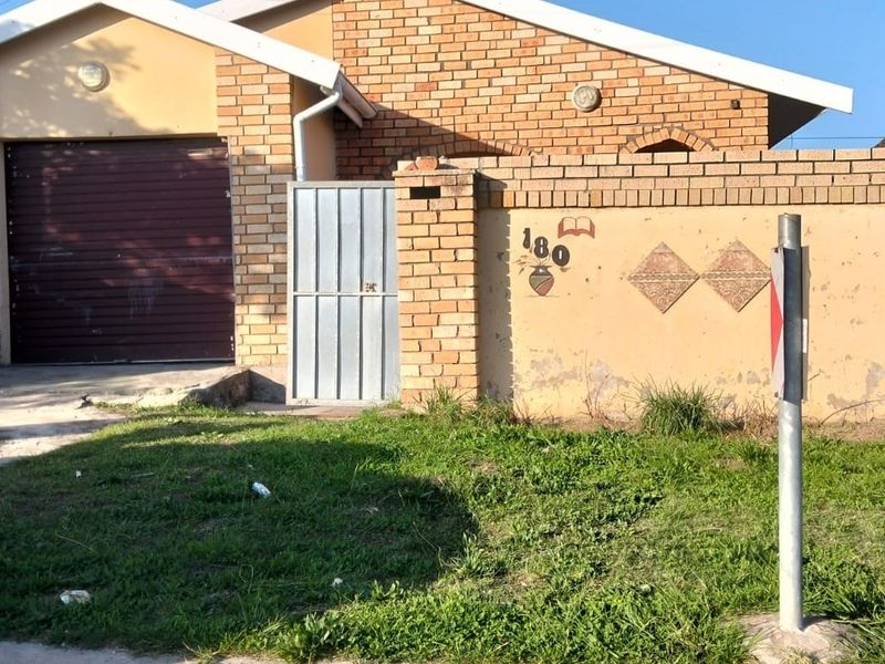 Front elevation of a face brick house featuring a single garage, pedestrian gate, and a perimeter wall with visible exterior maintenance requirements.