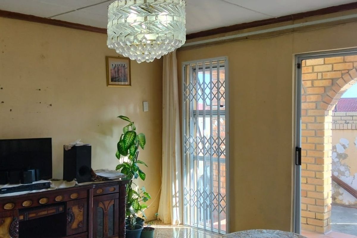 Living room featuring tiled flooring, a security gate, and access to an outdoor area with a brick archway.