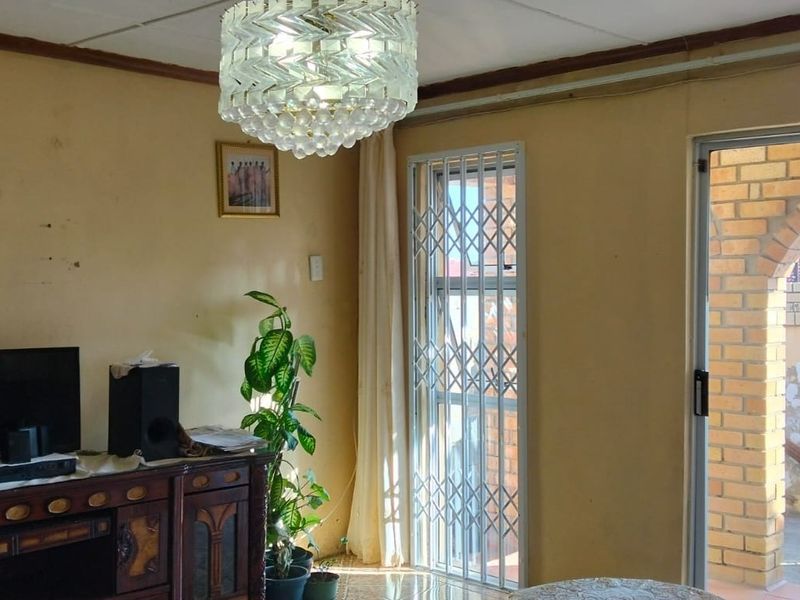 Living room featuring tiled flooring, a security gate, and access to an outdoor area with a brick archway.