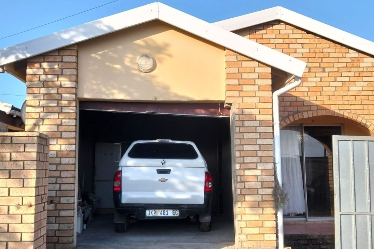 A residential garage featuring a face brick exterior facade with a concrete driveway and integrated gutter system.