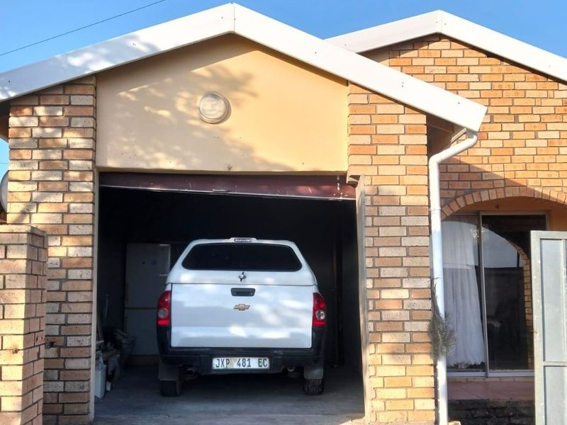 A residential garage featuring a face brick exterior facade with a concrete driveway and integrated gutter system.