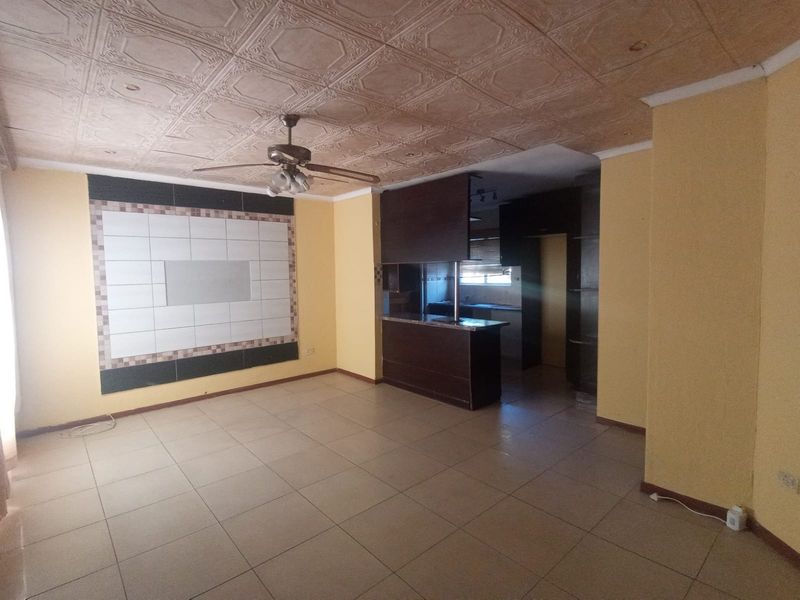 Open plan living area featuring tiled floors, a decorative ceiling, and a built-in kitchen with a breakfast bar.