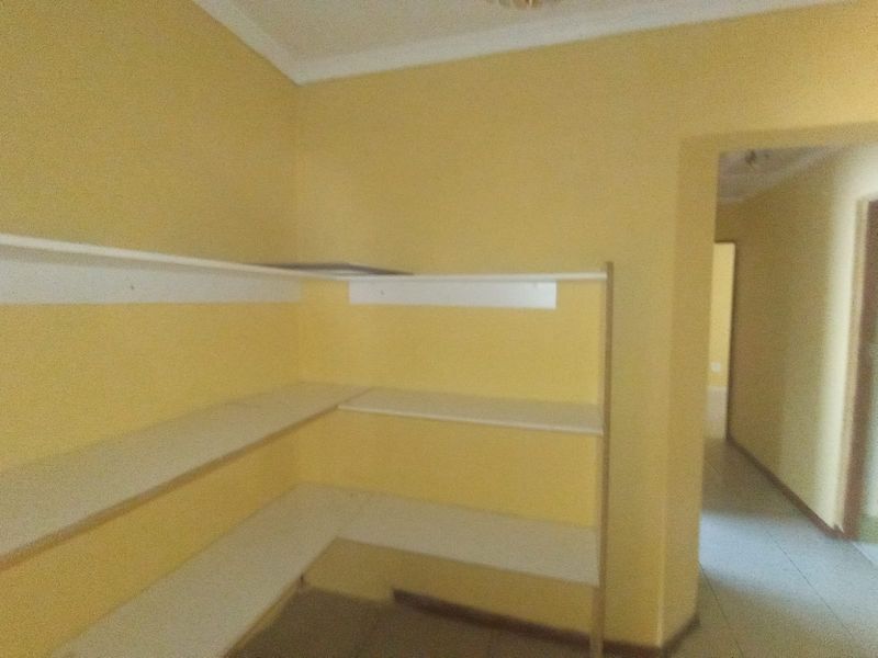 A functional scullery or pantry area featuring built-in shelving and yellow wall finishes, providing additional storage space.