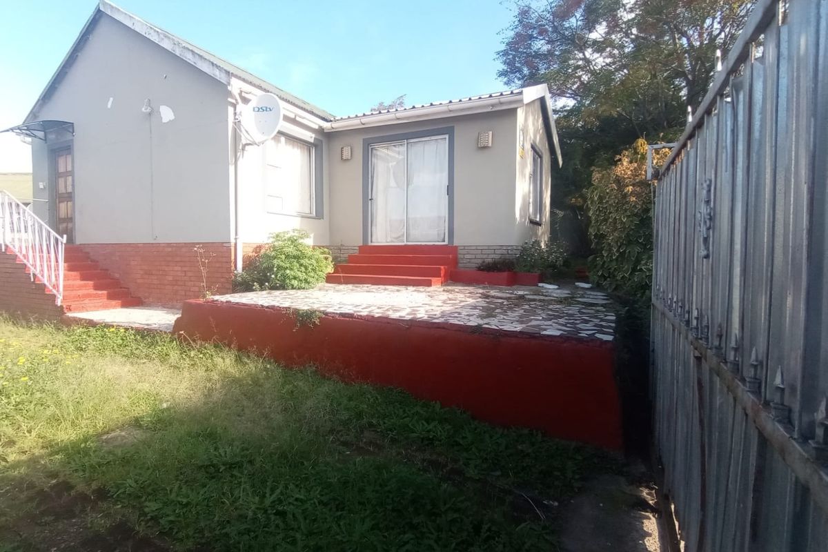 Rear exterior view of the house featuring a raised patio area, sliding glass doors, and a metal boundary gate.