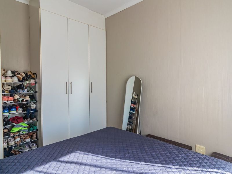 A bedroom featuring a built-in wardrobe with white cabinetry and neutral wall finishes.