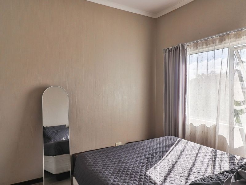 A bedroom featuring a built-in wardrobe, neutral wall finishes, and a window with curtain treatments.