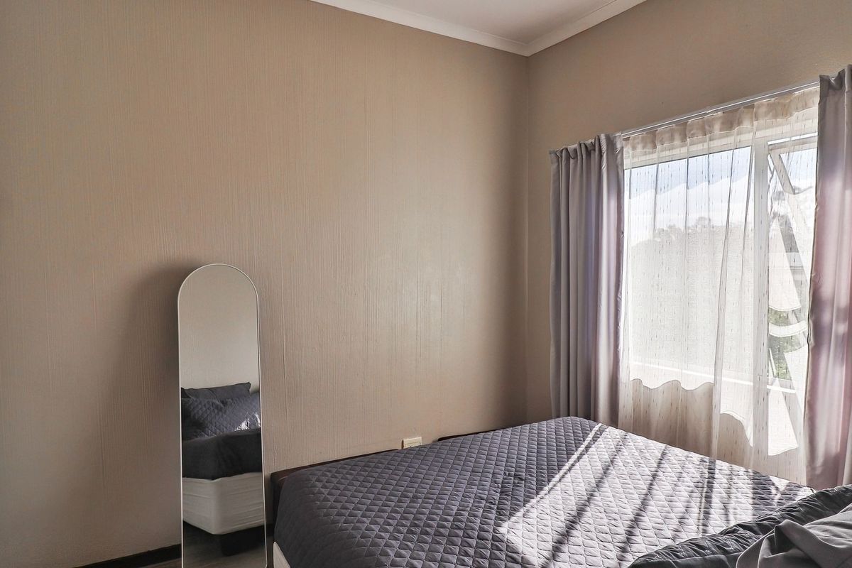 A bedroom featuring a built-in wardrobe, neutral wall finishes, and a window with curtain treatments.