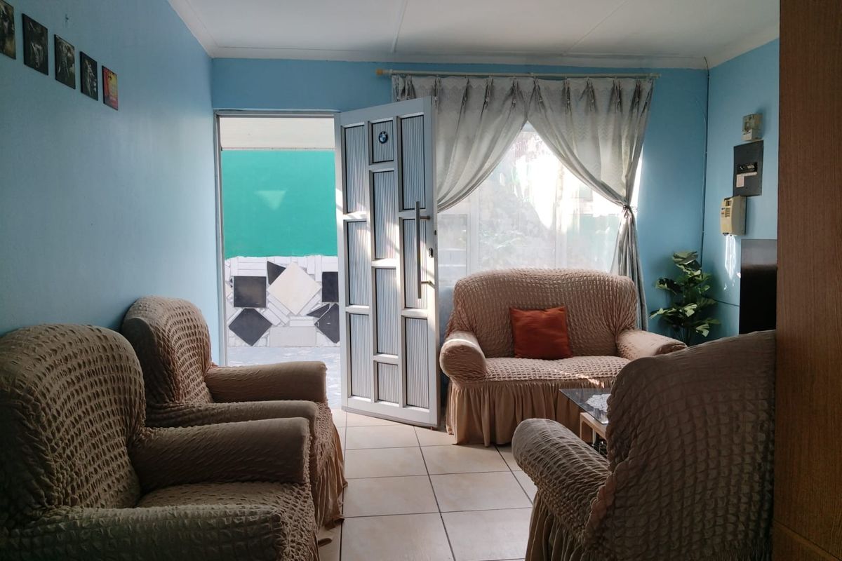 A living room featuring tiled flooring and an aluminium framed door leading to an outdoor area.