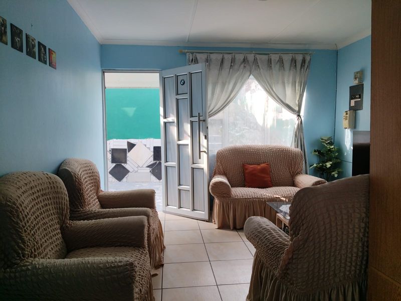 A living room featuring tiled flooring and an aluminium framed door leading to an outdoor area.
