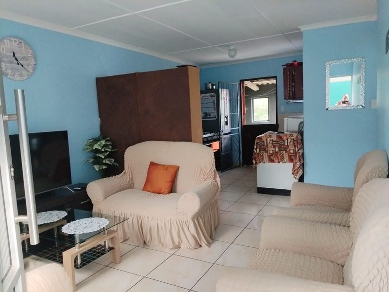 Open plan living area featuring ceramic floor tiles and a transition into the kitchen space with security gate access.