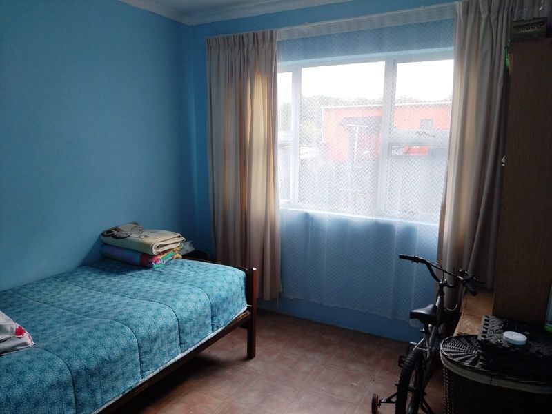 A functional bedroom featuring tiled flooring and a large window with natural light, providing a comfortable space for rest.