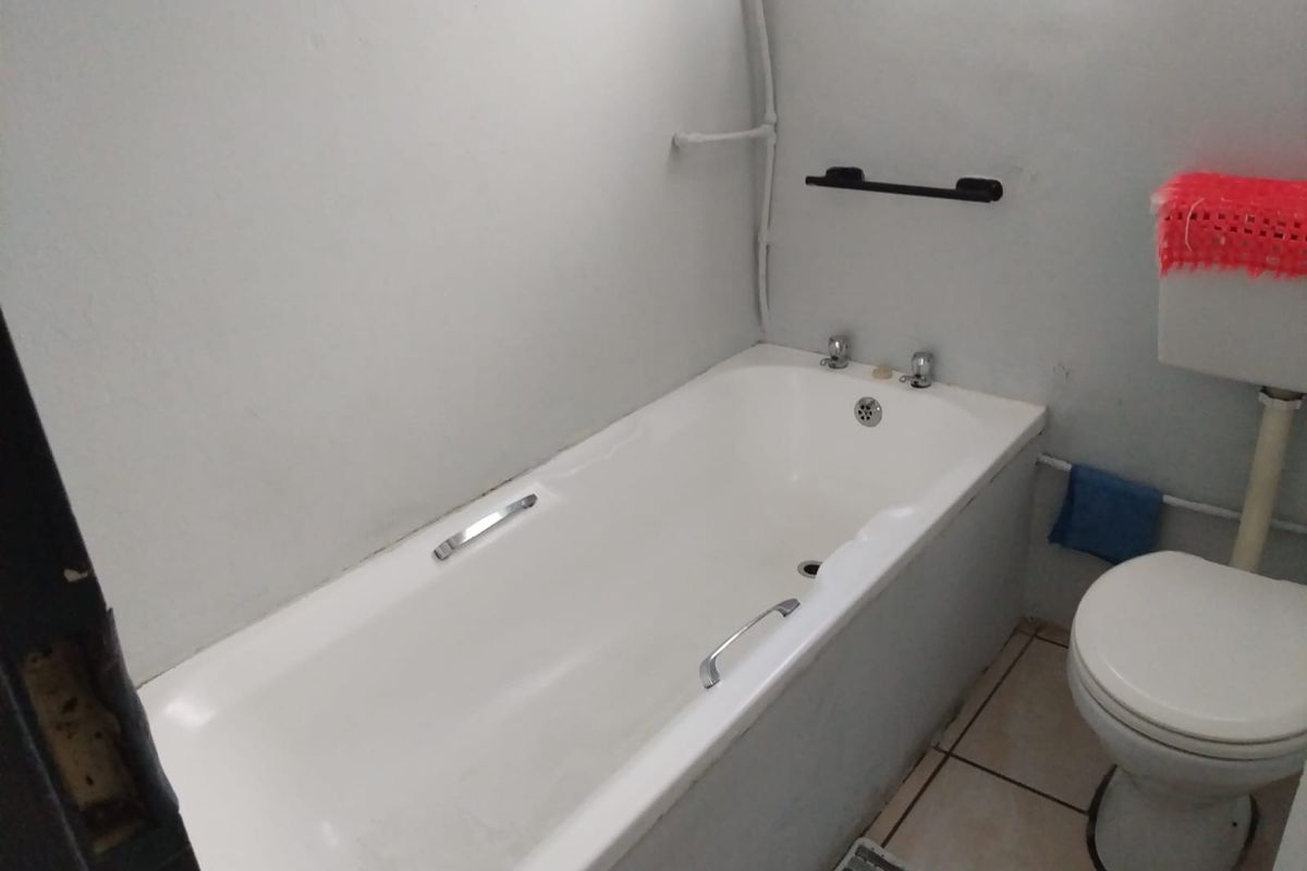 A functional bathroom featuring a standard bathtub, toilet, and tiled flooring, requiring cosmetic updates to improve its overall condition and aesthetic appeal.