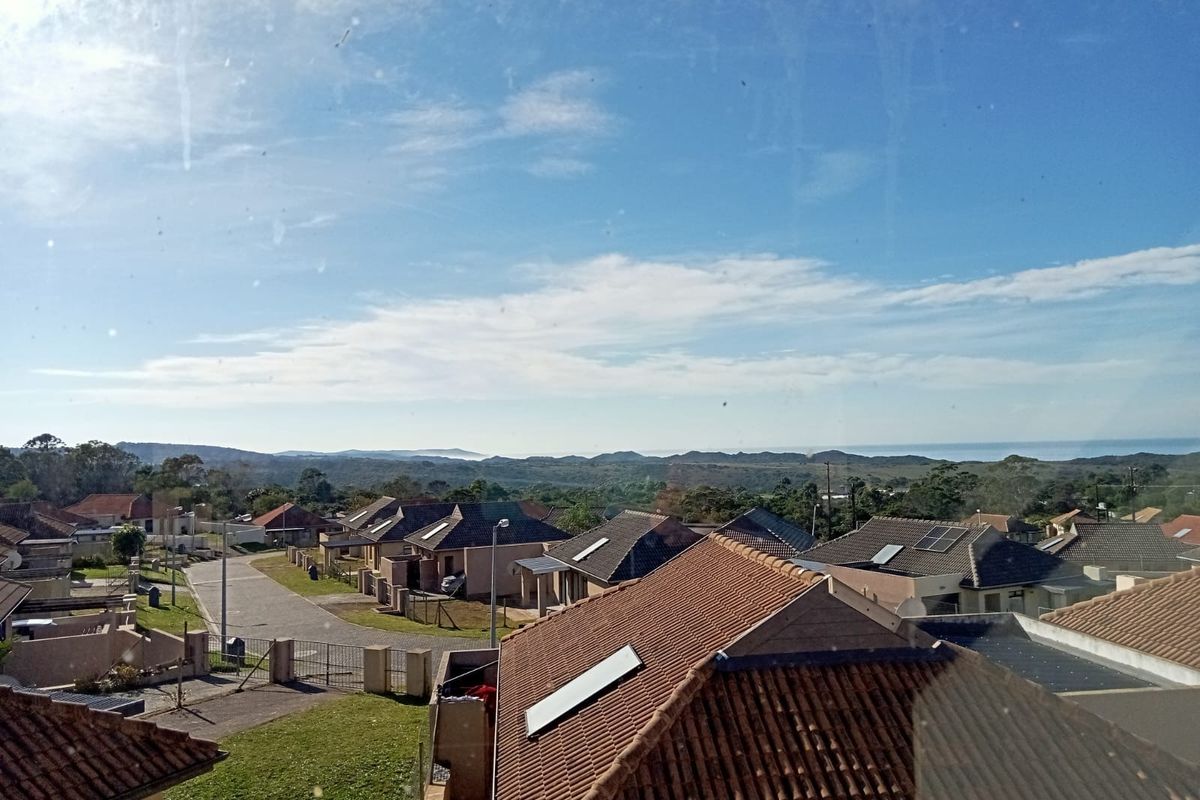 Elevated view overlooking a residential neighborhood with distant coastal landscape and horizon.