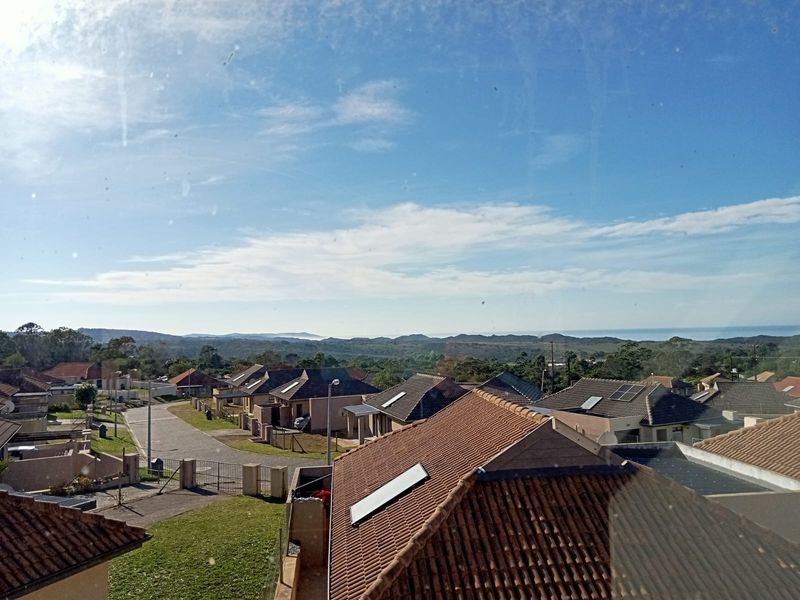 Elevated view overlooking a residential neighborhood with distant coastal landscape and horizon.