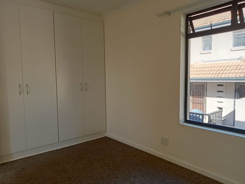 An empty bedroom featuring neutral walls, carpeted flooring, and built-in cupboards, providing a clean and versatile space ready for personalization.