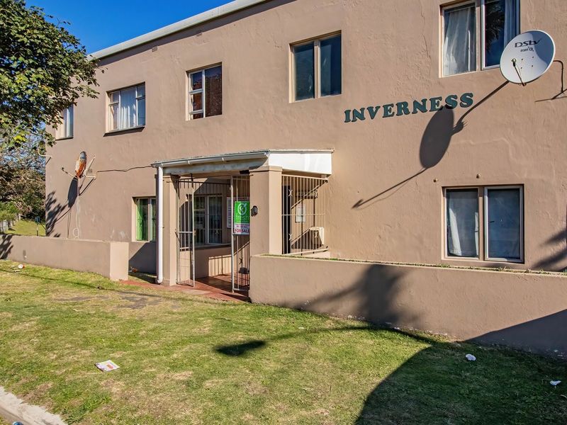 Front exterior view of the Inverness apartment building, featuring a paved entrance, security gate, and boundary wall.
