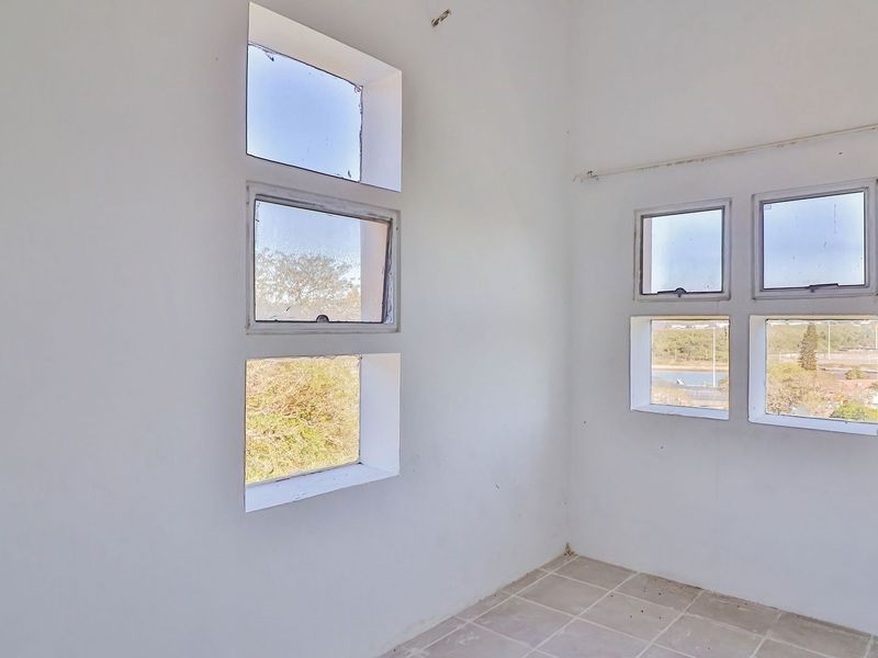 An empty bedroom featuring tiled flooring and multiple casement windows, offering a bright and blank canvas for potential renovation or interior design.