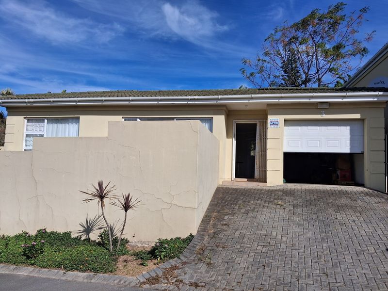 Front elevation of a townhouse featuring a paved driveway, single garage, and a private entrance with security gate.