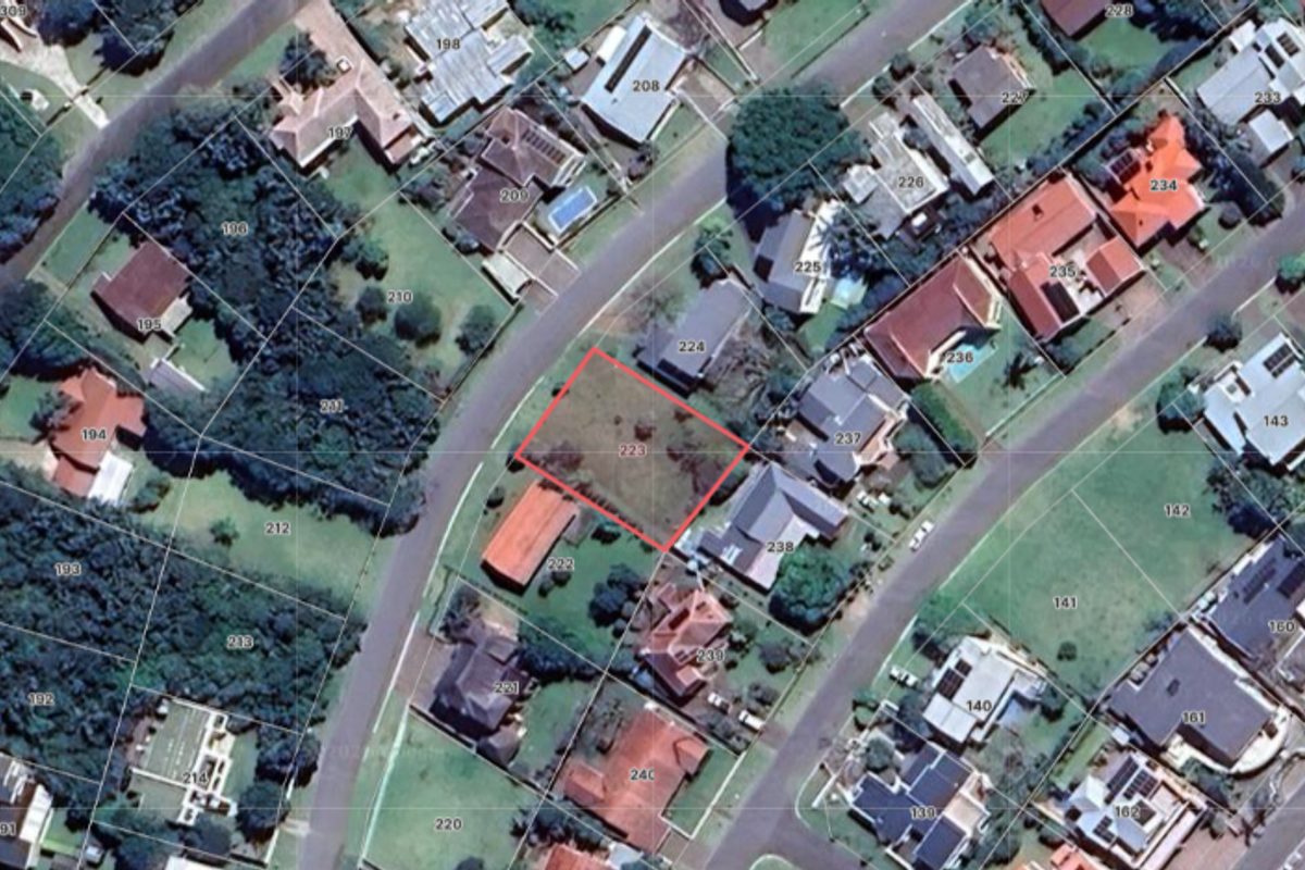 Aerial view of a vacant residential land plot, highlighted in red, situated within an established suburban neighborhood.