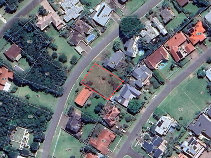Aerial view of a vacant residential land plot, highlighted in red, situated within an established suburban neighborhood.